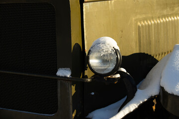 Headlight on a Dark Military or Heavy Vehicle Surrounded by Snow
