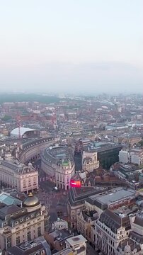 Stunning 4K aerial vertical video of London's Piccadilly Circus and Regent Street at dusk. Iconic cityscape with traffic, lights, historic architecture. Perfect for mobile social media travel content.