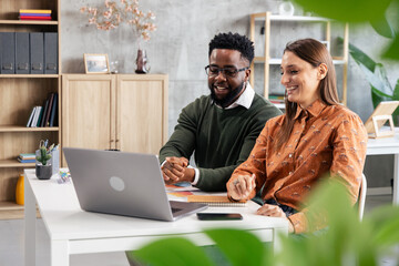 Diverse colleagues collaborating on laptop in modern office