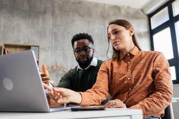 Diverse business professionals collaborating on laptop in office