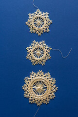 Snowflakes are made of straw on a blue background. Christmas decor. Top view. Straw weaving. Lutsk, Ukraine