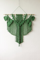 Green macrame leaves hanging on the wall. Macrame wall hanging for home decoration