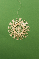 Snowflakes are made of straw on a green background. Straw snowflakes. Christmas decor. Straw star. Top view. Straw weaving. Lutsk, Ukraine