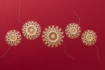 Straw snowflakes. Snowflakes are made of straw on a red background. Christmas decor. Top view. Straw weaving. Lutsk, Ukraine