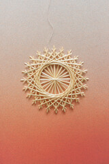 Snowflakes are made of straw on a orange background. Straw snowflakes. Christmas decor. Straw star. Top view. Straw weaving. Lutsk, Ukraine