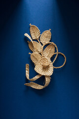 Decoration of straw on a blue background. Branch with flowers. Boutonniere made out of straw. Brooch. Straw weaving.