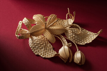 Decoration of straw on a red background. Branch with flowers. Boutonniere made out of straw. Brooch. Straw weaving.