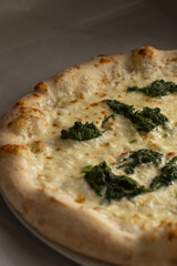 creamy white pizza topped with spinach and melted cheeses, golden bubbling crust and garlicky herb notes, vegetarian friendly