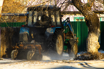 View of a Heavy Blue Utility Tractor Equipped with a Front Loader, Actively Pushing Snow by the Roadside