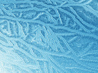 Beautiful ice patterns and sunlight on winter window glass, close-up natural texture