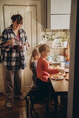 Mother pouring drink for children having breakfast at home