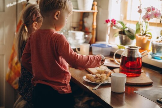 Young boy pouring honey on pancakes for breakfast - Powered by Adobe