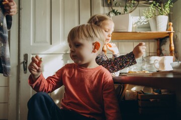 Children eating snack at home enjoying sunlight