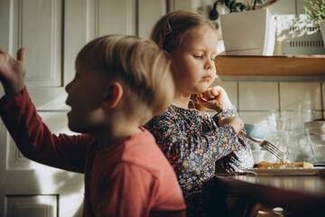 Children eating breakfast at home in sunlight