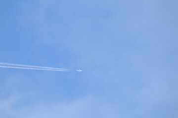 Skyward Bound: A sleek aircraft streaks across the cerulean expanse, leaving a trail of condensation that etches the boundless blue. Witness the dawn of air transport.