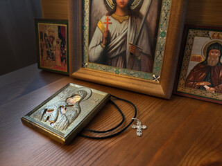 Orthodox icons and a cross on a wooden table, dark room. Madonna (Mary) of Jerusalem and a child (Jesus Christ) 