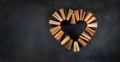 Vintage books arranged in a heart shape on a dark blue background for the design with copy space.