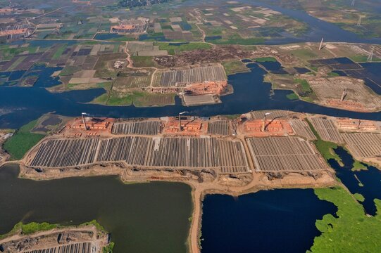 Aerial view of brick kilns and surrounding water bodies create a striking contrast of industrial activity amid natural wetlands, Aminbazar, Dhaka Division, Bangladesh.