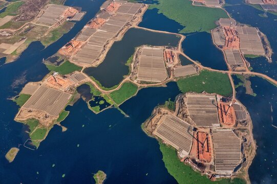 Aerial view of brick factories interspersed with dark water bodies and green vegetation, creating a textured landscape from above, Aminbazar, Dhaka Division, Bangladesh.