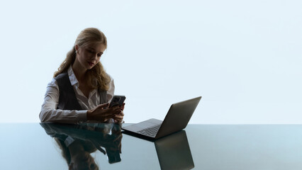 Focused woman checking phone while playing online casino on laptop. Concept of digital gambling, mobile payments, user anticipation and practical UX moments in everyday online play.
