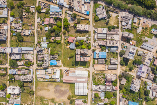 Aerial view of rooftops bask under the sun, a tapestry of urban life unfolding in geometric patterns, roads cutting through the landscape like precise lines, Bamburi, Mombasa, Kenya.