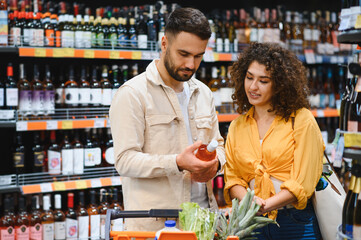 Couple choosing selection of alcohol in supermarket
