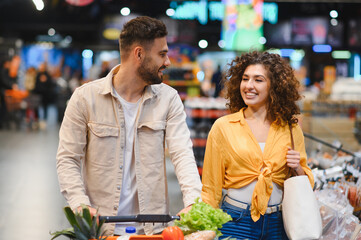 Happy young couple shopping for groceries at supermarket