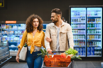 Couple shopping for fresh groceries in supermarket aisle