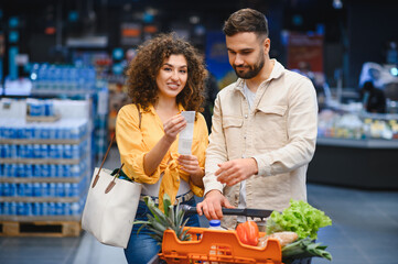 Couple checking grocery receipt while shopping in supermarket