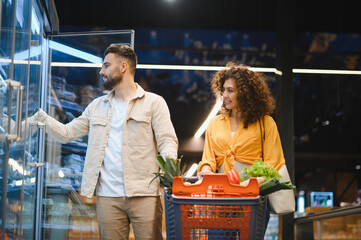 Couple grocery shopping frozen food in supermarket aisle