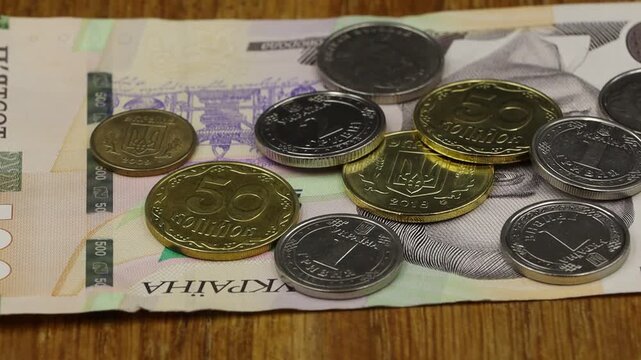 Close-up of Ukrainian hryvnia coins stacked on a wooden surface, rotating.