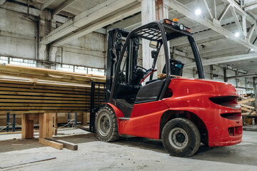 Red forklift inside a warehouse used for handling wooden material
