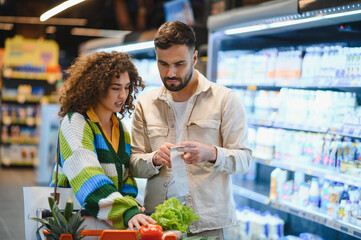 Couple checking grocery list in supermarket aisle