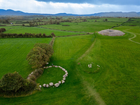 Aerial view of ancient stone circles and passage tombs punctuate the vibrant green landscape under a vast sky, Carrowmore, County Sligo, Ireland.