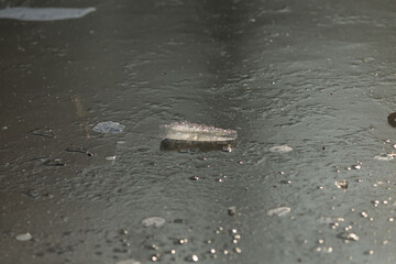 A small object is seen resting on a wet surface that accumulates during the rainfall from a distant storm