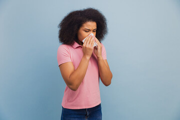 African American woman blowing nose using tissue