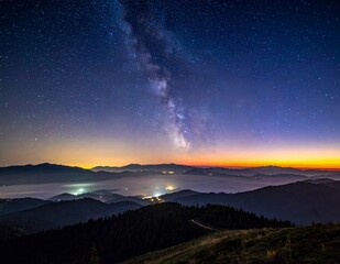 Milky Way Galaxy over Mountain Landscape at Twilight with City Lights Below.
