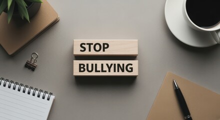 Wooden blocks spelling STOP BULLYING on gray office desk with notebook, pen, coffee and folder, concept of workplace ethics, respect, awareness and inclusion against harassment