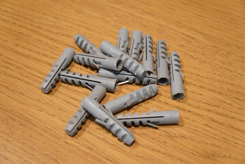 Gray plastic wall anchors scattered on a wooden surface
