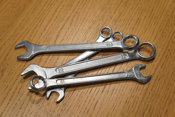 Close-up of various wrenches arranged on a wooden surface, ready for use