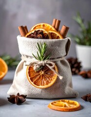 Jutebeutel gef&uuml;llt mit getrockneten Orangen, Zimtstangen und Sternanis auf einer grauen Oberfl&auml;che.
