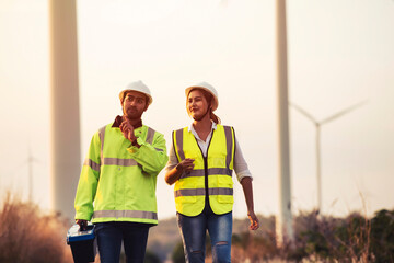 Young Asian maintenance engineers team working in wind turbine farm at sunset. © Pituk