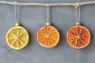 Dried citrus slice christmas ornament hanging on rope with gray background festive decoration natural style