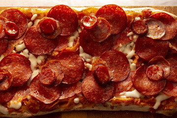 Stacked pepperoni with melted cheese on flatbread crust, Melted mozzarella with pepperoni slices on crispy rectangular bread