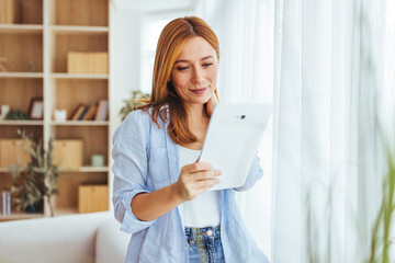 Woman Using Tablet Near Bright Window in Modern Home Office Setting, Calm and Focused