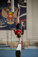 Junior girl perform an exercise on balance beam gymnastics competition