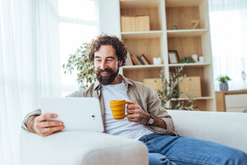 Relaxed Man Working on Tablet at Home with Yellow Mug in Cozy Living Room