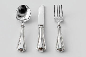 A silver cutlery set of a spoon, a fork and a knife as  elegant fine-dining tableware with polished stainless steel texture