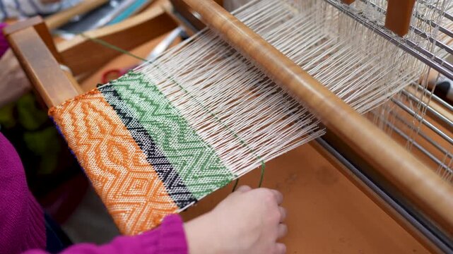Hands of child carefully weaving on loom on master class. Weaving as hobby for fine motor skill improvement, skillful handwork. Creative handmade activity in traditional craft interest for kids.