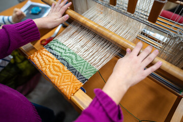 Hands of child weaving on loom with joy of crafting. Creative handmade activity in traditional crafts for kids. Weaving as hobby for fine motor skill improvement, imaginative, skillful handwork. 